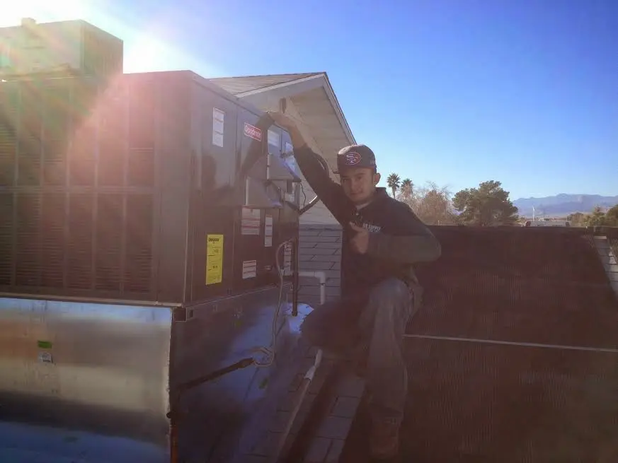 HVAC technician performing Air Duct Repair on a rooftop unit in Manville